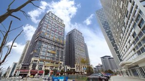 A high-rise building with multiple floors, surrounded by other tall buildings and a clear sky. - Vyluk Hotel Chongqing Airport (Chongqing)