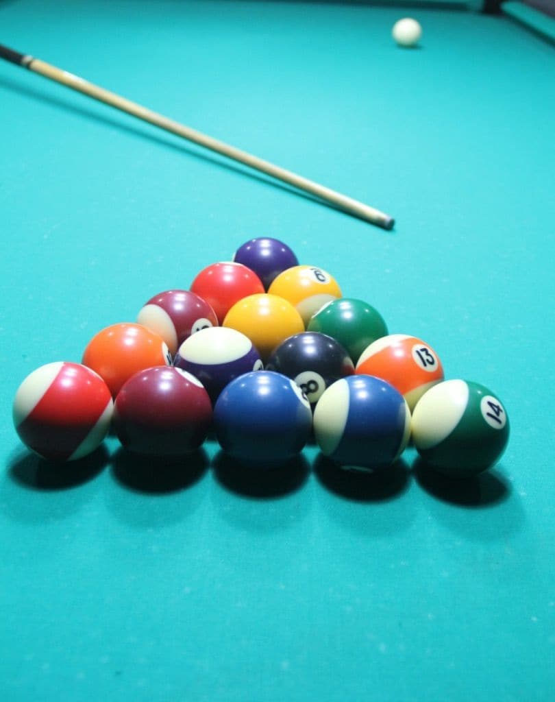 A pool table with a set of billiard balls arranged in a triangle formation.