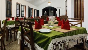 Un espace repas avec des tables dressées pour le repas, agrémenté de nappes vertes, de chaises en bois et de serviettes rouges.
