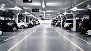 Een meerlaagse ondergrondse parkeergarage met auto's in rijen, pijlen op de vloer die de richting aangeven, en borden met informatie over toiletten en uitgangen.