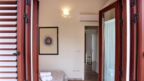 A bedroom with a bed, a framed picture on the wall, and a hallway leading to another room. - Residence Bianco Navarrese B (Baunei)