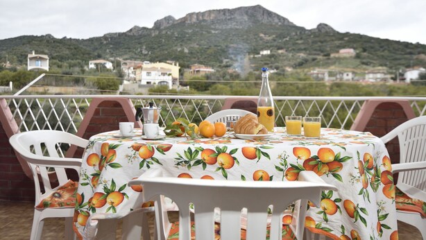 A table set for breakfast with a mountain view in the background. - Casa di Zio Mario A (Baunei)