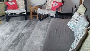 Een woonkamer met een bank, twee fauteuils, een bijzettafeltje en een plafondventilator.