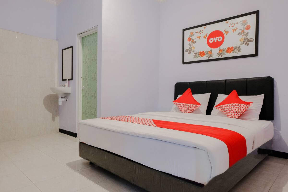 Une chambre d’hôtel avec un lit, une table de chevet, un miroir et un tableau encadré au mur.