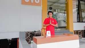 A reception desk with a sign that reads "OYO" and a person standing behind it. - OYO 894 Nusa Indah Homestay Syariah (Batu)