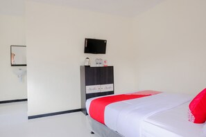 Un dormitorio con cama, televisión montada en la pared, armario y lavamanos.