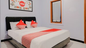 A neatly made bed with white and red bedding, a black headboard, and a framed artwork above it. - OYO 894 Nusa Indah Homestay Syariah (Batu)