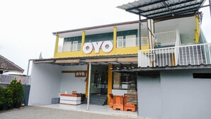 A two-story building with a prominent 'OYO' sign, a balcony with white railings, and a staircase leading to the entrance. - OYO 894 Nusa Indah Homestay Syariah (Batu)