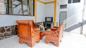 A living room with a sofa set, a television, and a staircase. - OYO 894 Nusa Indah Homestay Syariah (Batu)