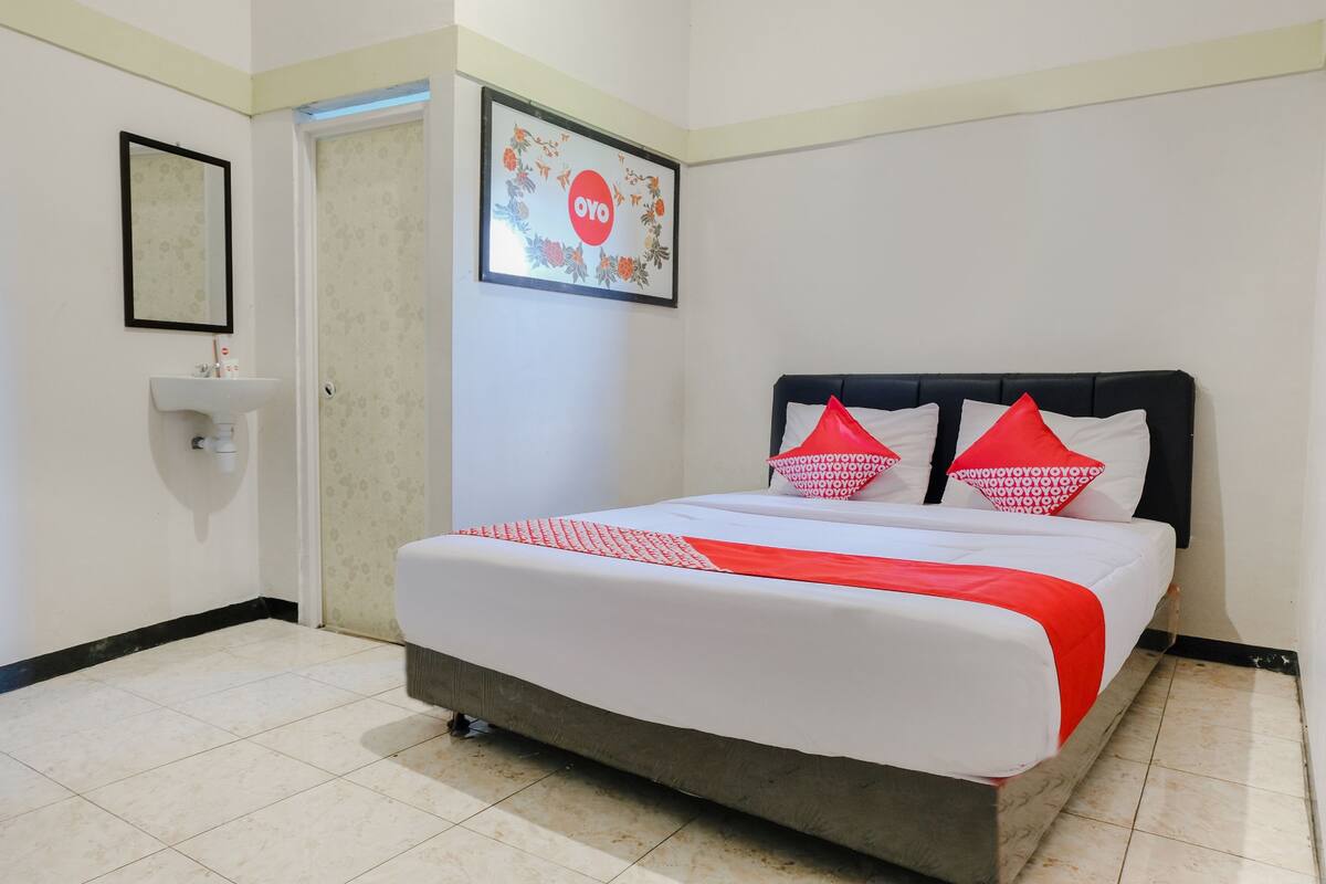 Une chambre d’hôtel avec un lit, un lavabo, un miroir et un tableau encadré au mur.
