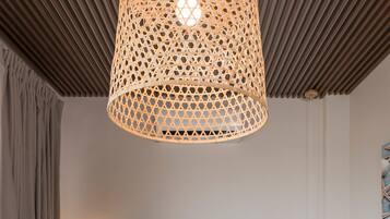 A hotel room with a bed, two bedside tables, a wall-mounted lamp, and a hanging light fixture.