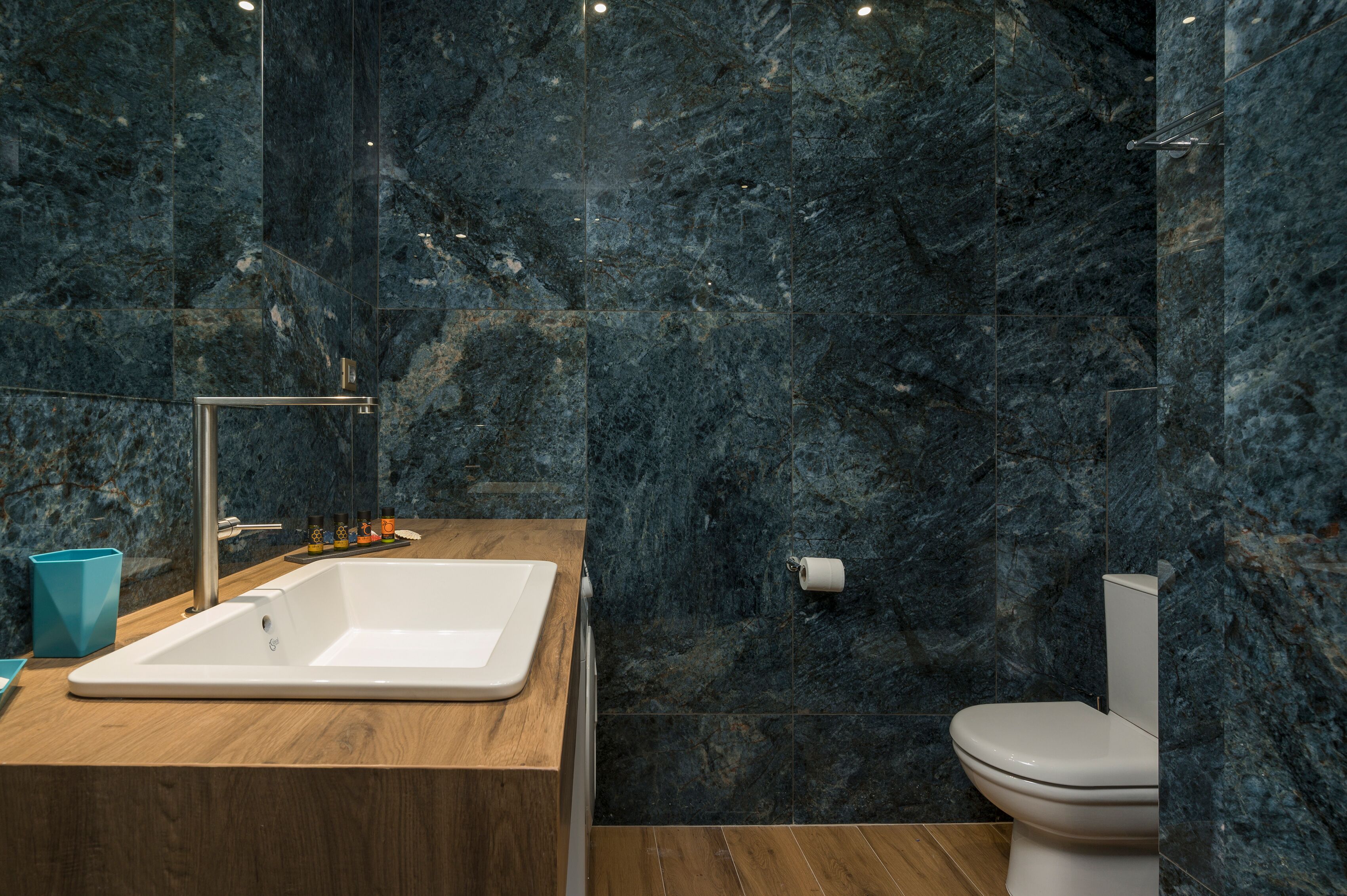 A modern bathroom with a wooden vanity, a white sink, and a toilet.