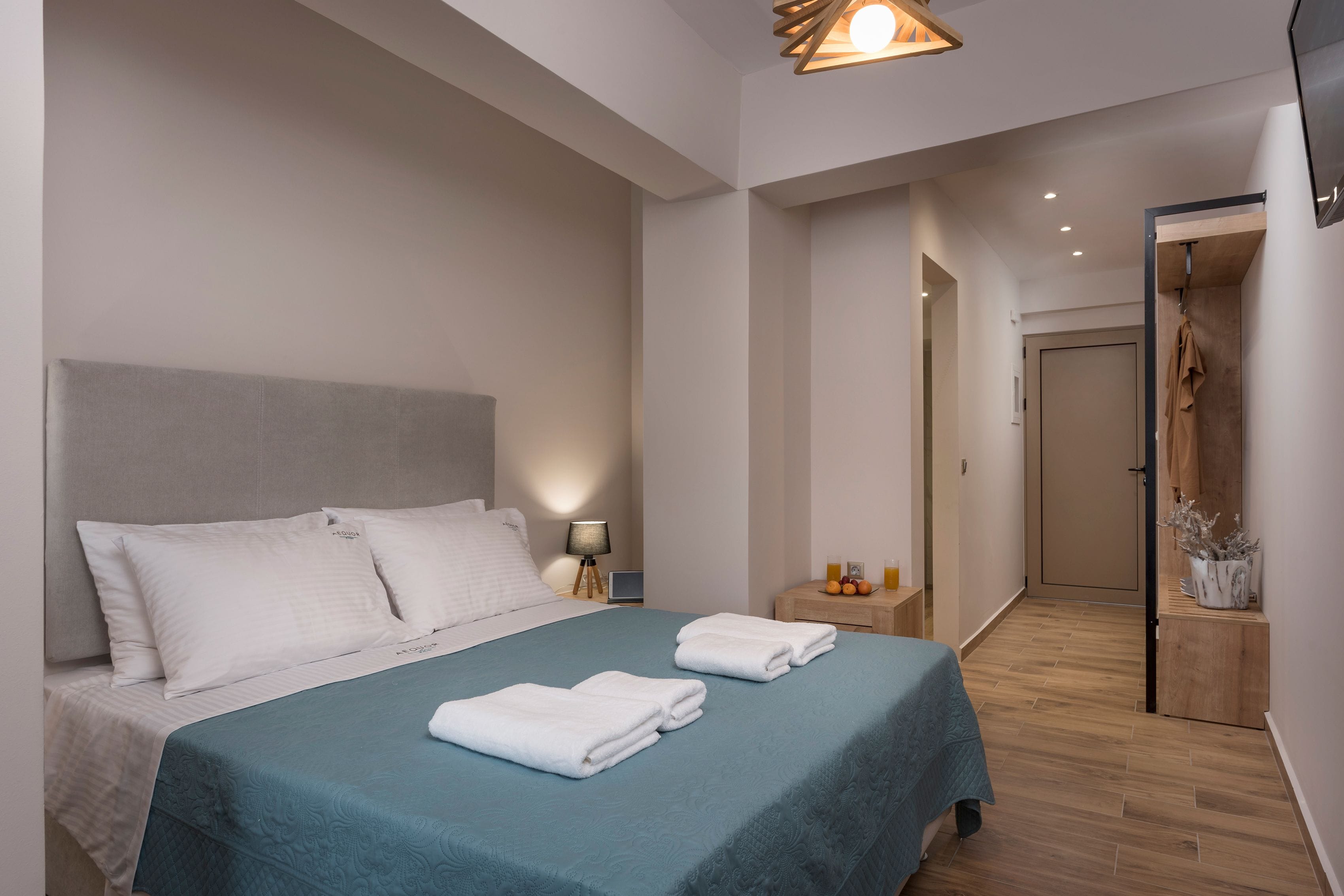Ein modernes Hotelzimmer mit einem großen Bett, einem Nachttisch mit Lampe und Holzboden.