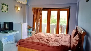 Una camera da letto con un letto, una scrivania, una sedia, un condizionatore d'aria e una finestra con tende.