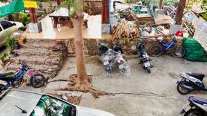 Un cortile con un albero, una targa che indica la sala comune e diversi oggetti come biciclette e scooter.