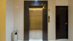An elevator with a digital display, a trash can, and a black door. - Halim Hotel (Tanjung Pinang)