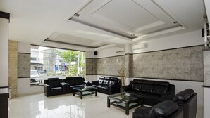 A modern lobby with black leather sofas, a glass coffee table, and a marble wall. - Halim Hotel (Tanjung Pinang)