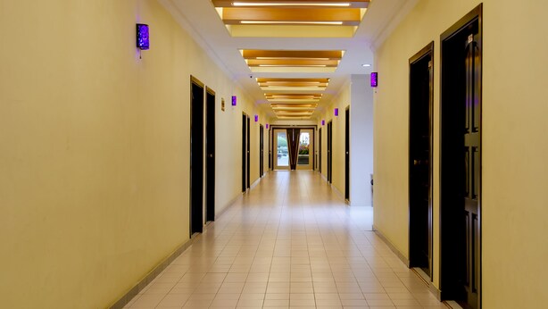 A hotel corridor with a modern design, featuring a long hallway with doors on both sides, a tiled floor, and recessed lighting on the ceiling. - Halim Hotel (Tanjung Pinang)