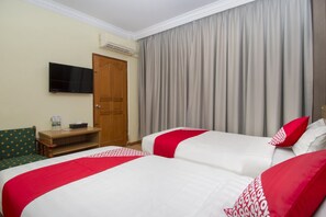 A hotel room with two beds, a television, a desk with a chair, and a door. - Halim Hotel (Tanjung Pinang)