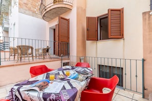 A table set with a tablecloth, chairs, and a small table with food and drinks. - Casa Goloritzè (Baunei)