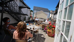 An outdoor patio area with tables and chairs, a staircase, and a building with large windows. - Dovey Inn (Aberdovey)
