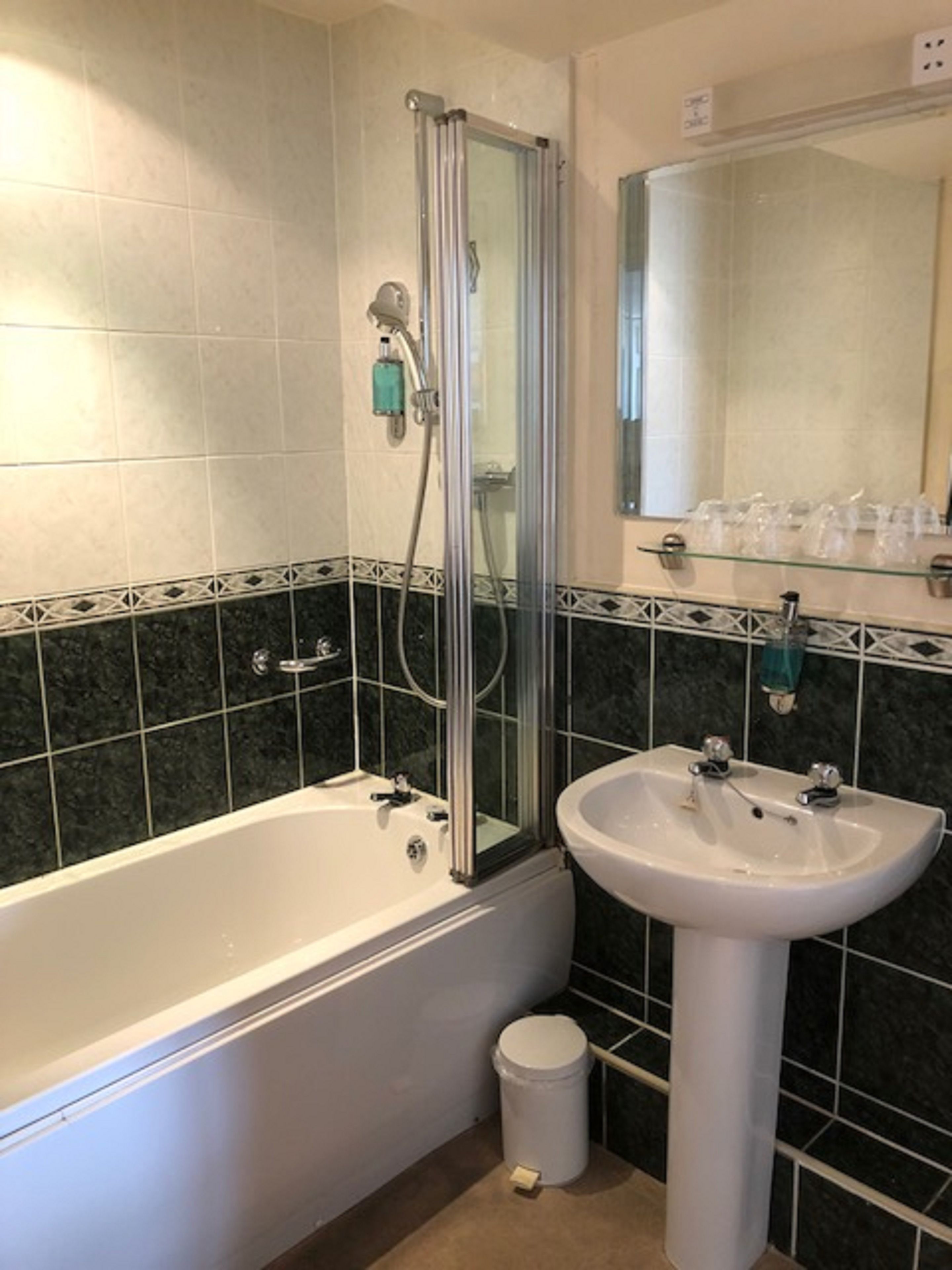 A bathroom with a bathtub, a sink, and a glass shower enclosure.