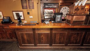 A reception desk with a clock, a coffee machine, and a menu board in a hotel lobby. - Dovey Inn (Aberdovey)