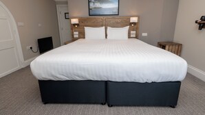 A neatly made double bed with a headboard, two bedside tables, and a wall-mounted picture. - Dovey Inn (Aberdovey)