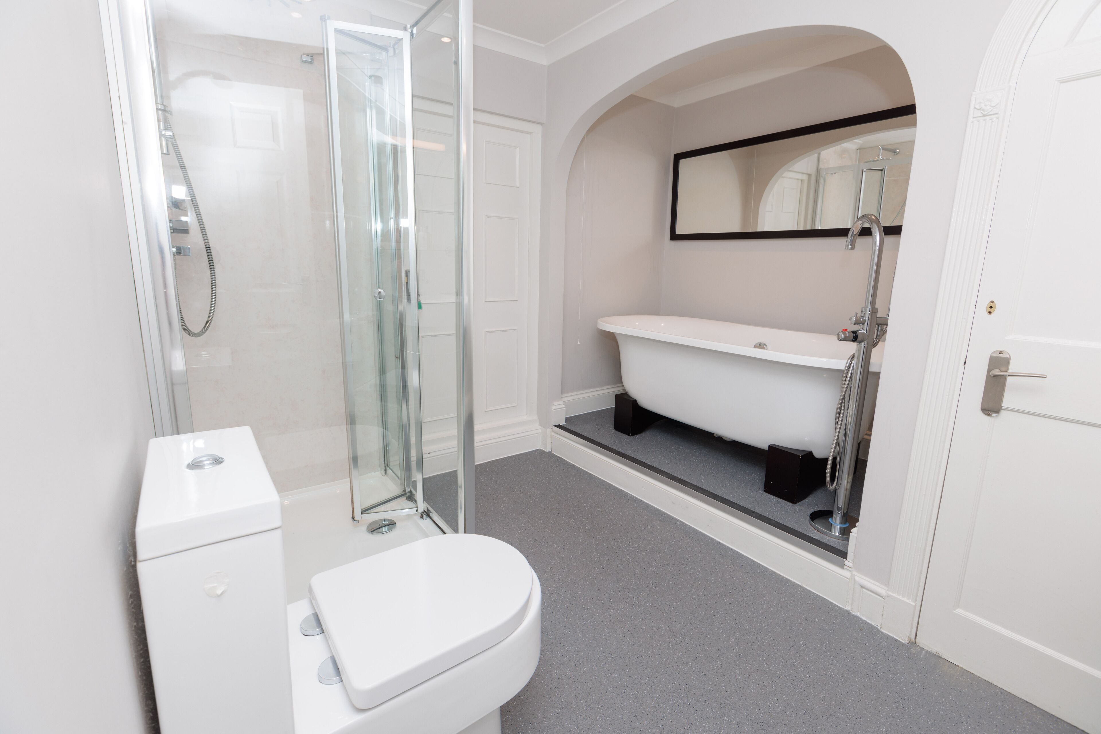 A modern bathroom with a glass-enclosed shower, a white toilet, and a freestanding bathtub.