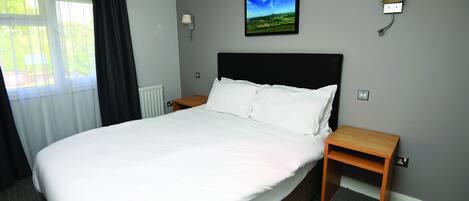 Una cama bien hecha con sábanas blancas en una habitación de hotel.