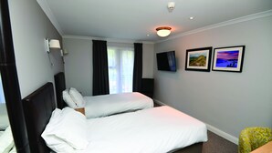 Habitación de hotel con dos camas, un televisor de pantalla plana y dos cuadros en la pared.