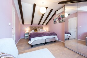 A bedroom with a bed, bedside tables, a mirror, and a ceiling with exposed beams.