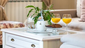 A white bedside table with a glass top, a white nightstand with drawers, a potted plant, a glass of orange juice, and a plate with a chocolate dessert. - Vacation house Cavtat (Konavle)