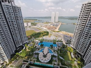 A high-rise building with a central courtyard featuring a swimming pool and a large flower-shaped structure. - Teega Suites by Squarenest (Iskandar Puteri)
