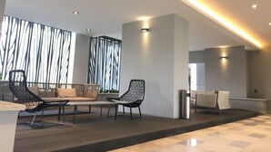 Eine moderne Lobby mit Sitzgelegenheiten, einem Empfangsbereich und einer Wand mit Muster.