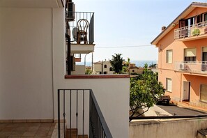 A residential building with a balcony, a staircase, and a view of neighboring houses.