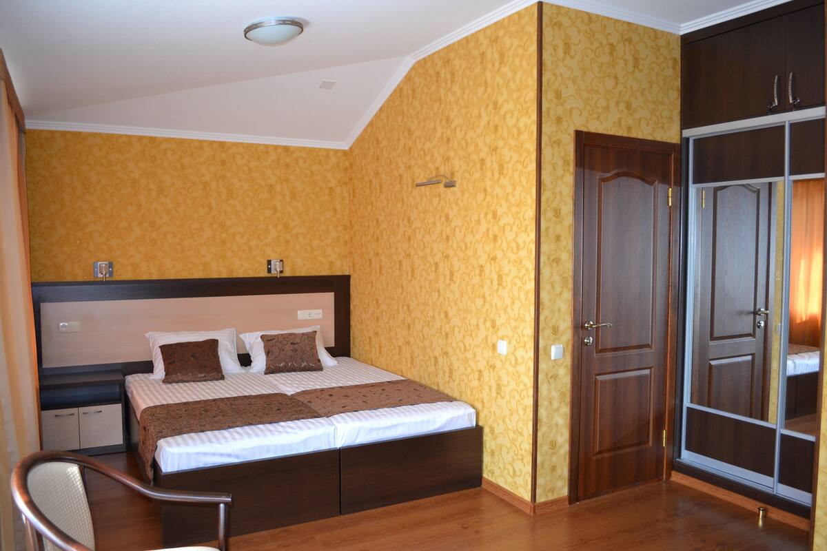 A bedroom with a bed, a chair, a wardrobe, and a door.