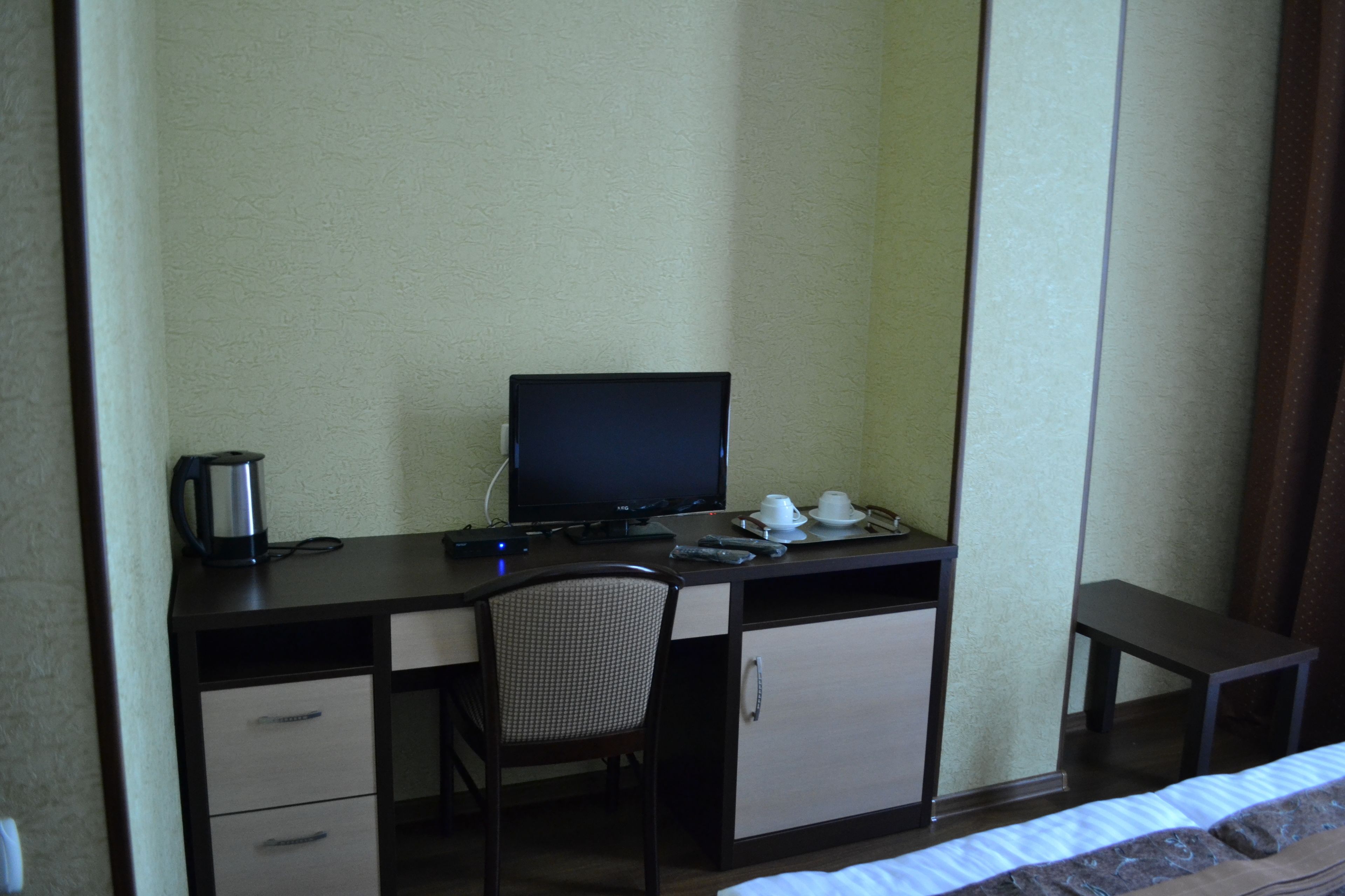 Une chambre d’hôtel comprenant un lit, un bureau avec un ordinateur, une chaise, une petite table et une machine à café.