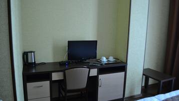 Une chambre d’hôtel comprenant un lit, un bureau avec un ordinateur, une chaise, une petite table et une machine à café.