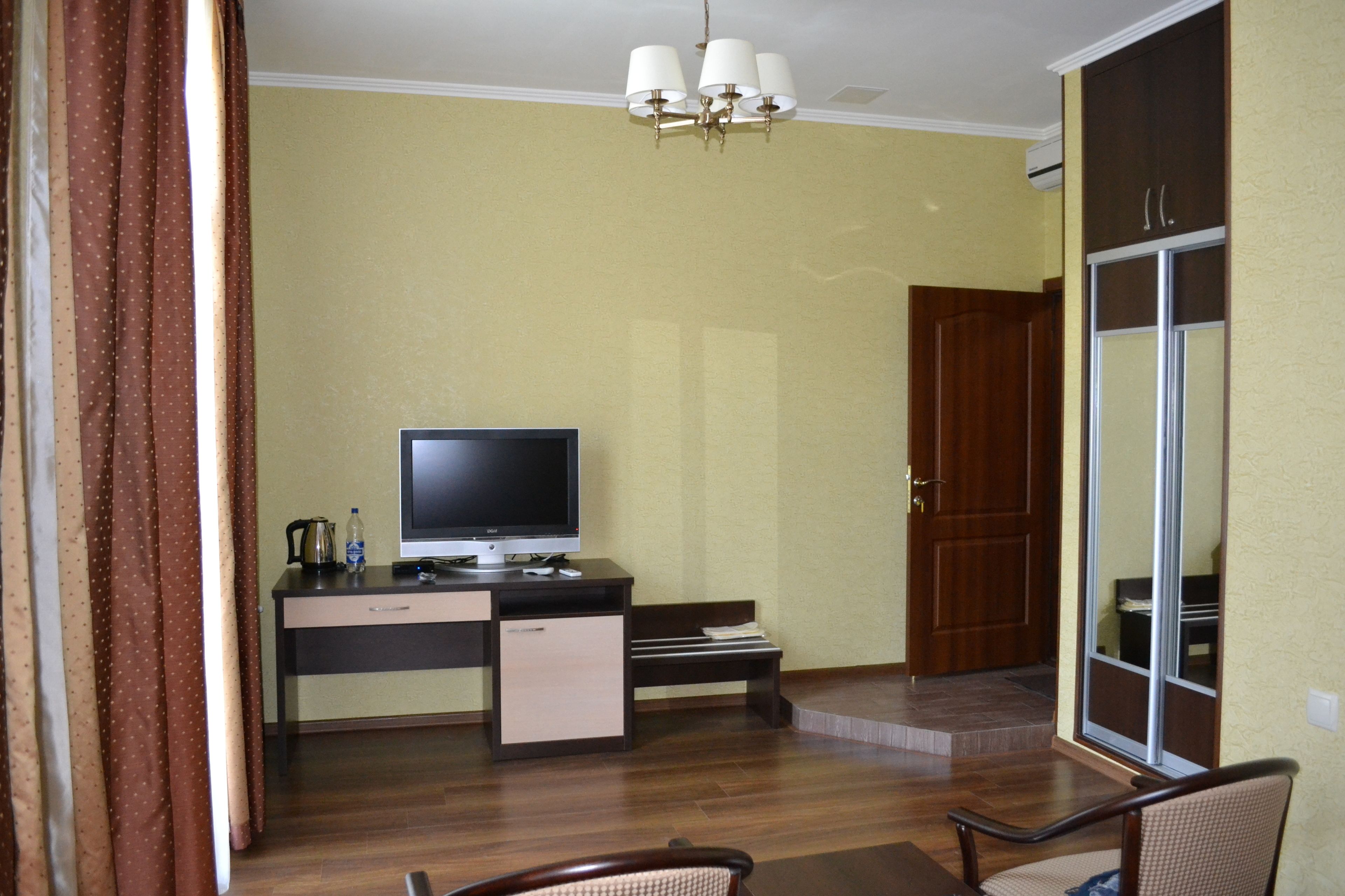 Hotelkamer met een bureau, televisie en een schuifdeur naar een balkon.