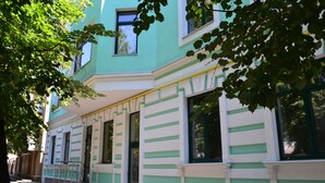A building with a green and white facade, large windows, and a staircase leading to the entrance. - Paloma House (Kharkiv)