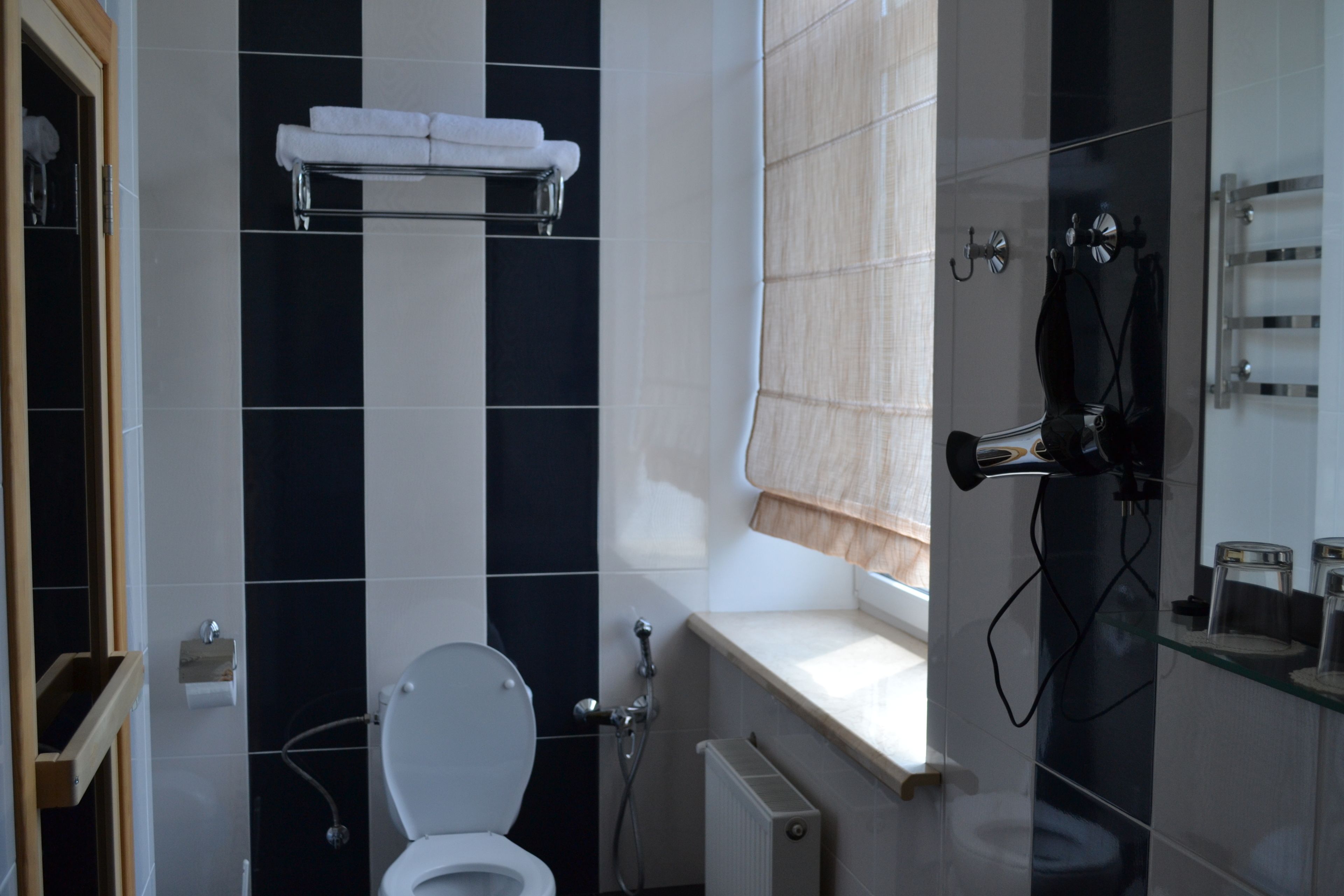 A bathroom with a toilet, a towel rack, a shower area, and a glass shelf with toiletries.
