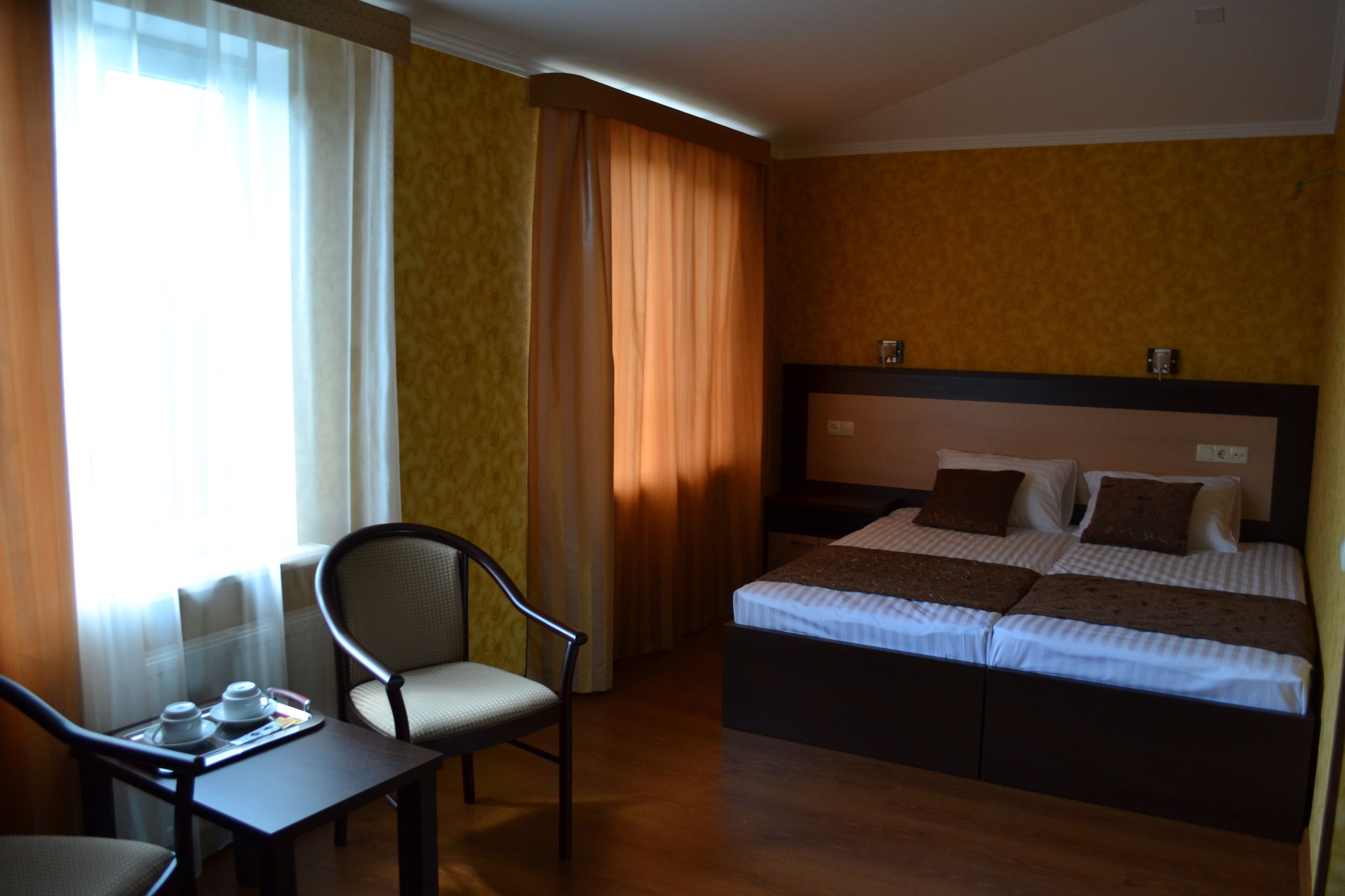 Una habitación de hotel con cama, una silla, una mesa y cortinas.