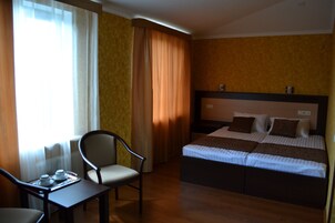 Una habitación de hotel con cama, una silla, una mesa y cortinas.