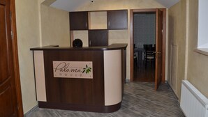 A reception desk with a sign reading "Paloma House" in a hotel lobby with a tiled floor and a wooden door. - Paloma House (Kharkiv)