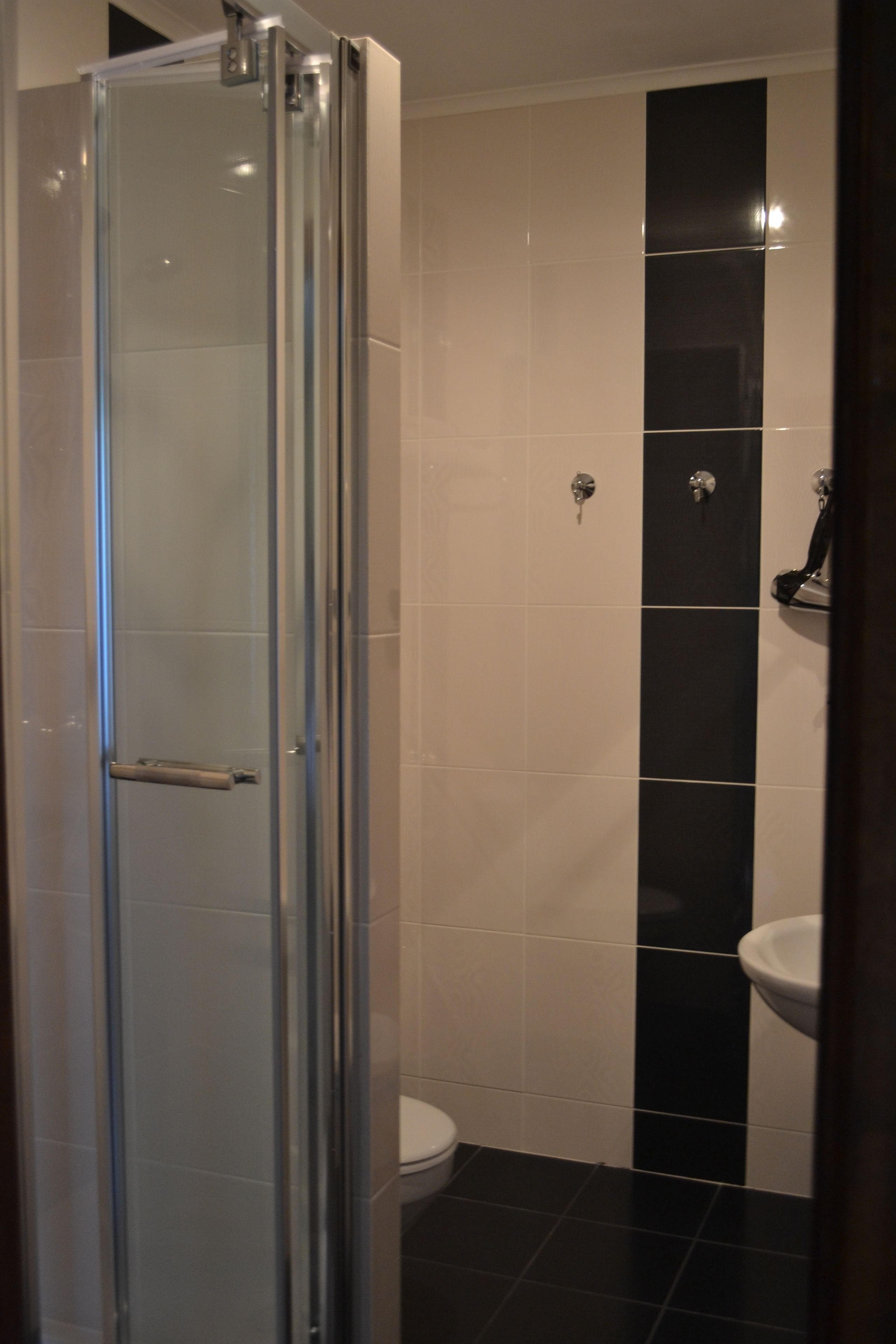 A bathroom with a glass shower enclosure, a toilet, and a sink.