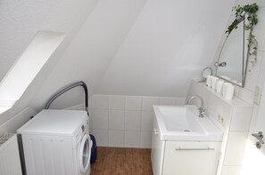 Un baño moderno y compacto con lavadora, lavamanos y espejo.