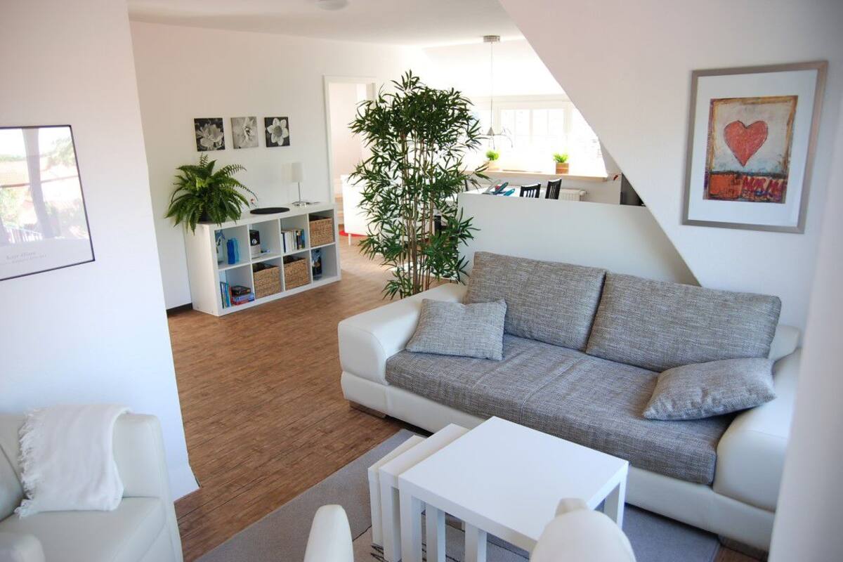 A modern living room with a white sofa, a coffee table, and a bookshelf.