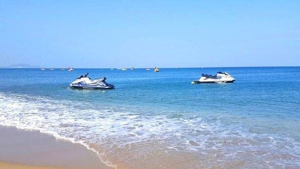 Ein Strand mit zwei Jetskis auf dem Wasser und einem sandigen Ufer.