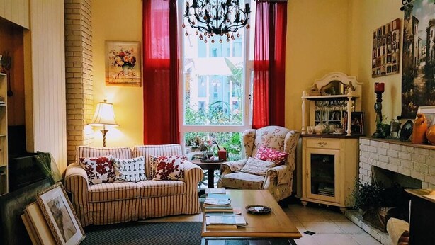 Una sala de estar acogedora con un sofá a rayas, un sillón estampado, una mesa de centro de madera y una chimenea.